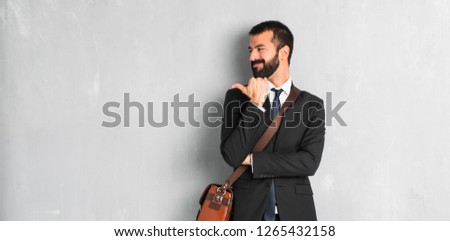 Businessman with beard pointing to the side with a finger to present a product