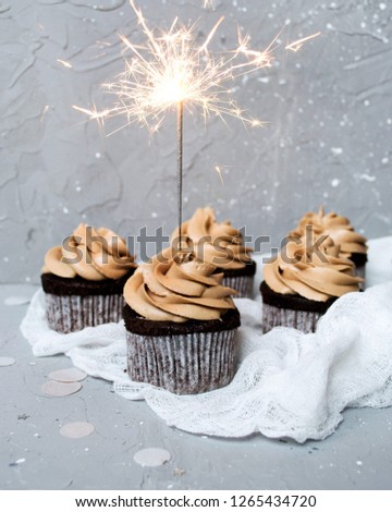 Chocolate muffins with sparkler on a gray background. Festive cupcake