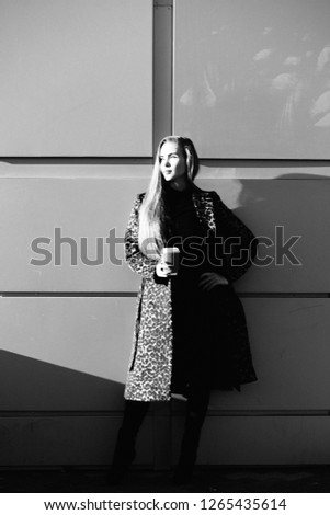 Beautiful stylish woman in the street drinking morning coffee in sunshine light,black and white