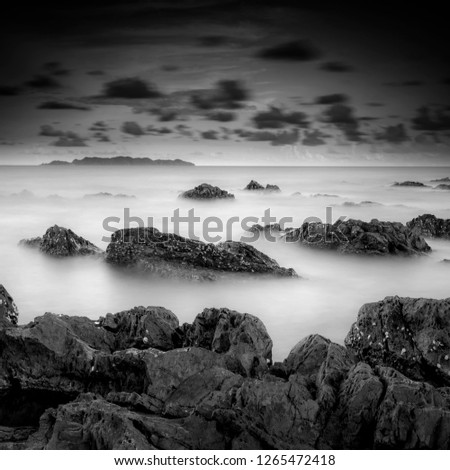 seascape rocky beach in black and white, A slow shutter speed was used to see the movement ( Soft focus due to long exposure shot ) 
