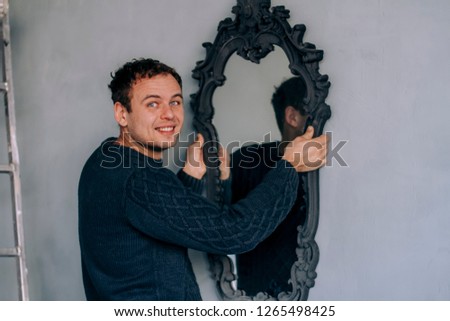 A man hangs a mirror on the wall