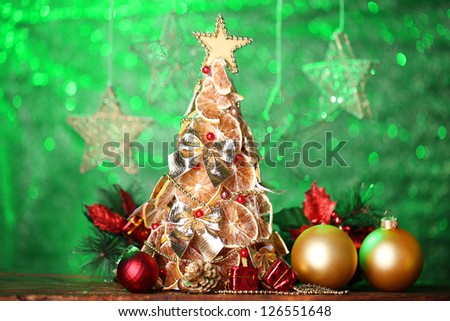 beautiful christmas tree of dry lemons with decor, on green background