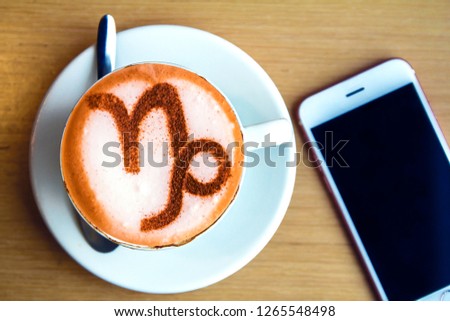 A cup of cappuccino coffee with a zodiac sign pattern Capricorn Cinnamon on milk foam