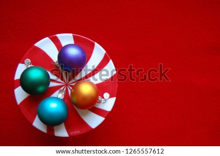 Top view of Peppermint Christmas composition, holiday decoration with colorful ornaments on red background, copy space