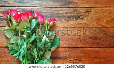 Red rose on wooden table top view with space for decoration background on Valentine's day and wedding events.