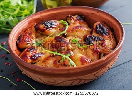 Baked chicken wings in bowl on wooden table.