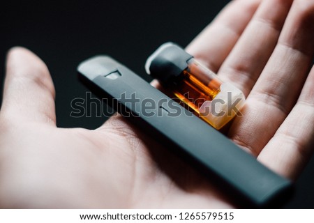 Disposable vape pen with refill pod on hand Royalty-Free Stock Photo #1265579515