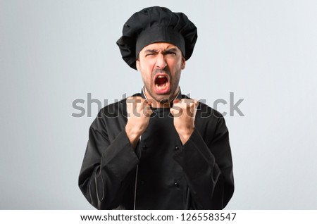 Chef man In black uniform annoyed angry in furious gesture. Frustrated by a bad situation on grey background