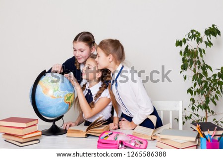 three girls in the classroom studying geography globe of planet Earth