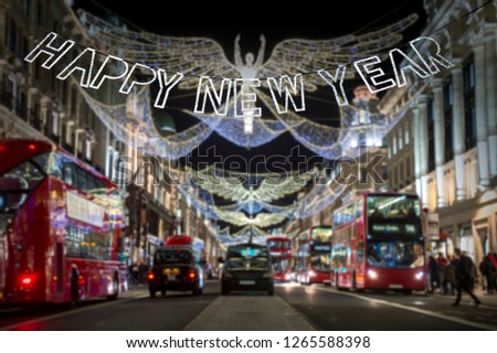 Happy New Year message in shiny silver lettering hanging in front of holiday traffic scene of Regent Street, London at night