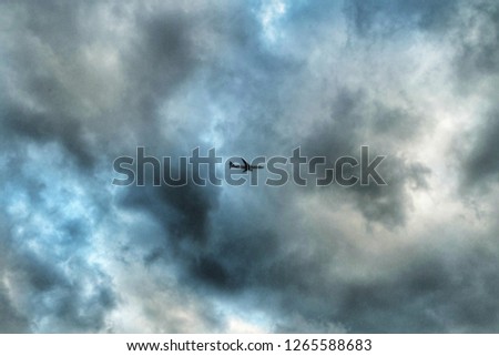 A picture of an aeroplane flying at th cloudy sky in London, United Kingdom.
