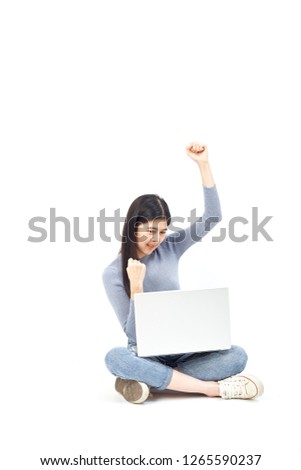 Business concept. Portrait of a smiling casual girl holding laptop computer while sitting on a floor and happy gesture on white background