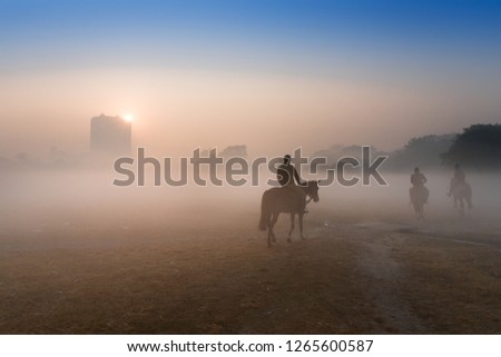 Three mounted polices walking thier horses at Kolkata maidan, in a foggy winter morning.
