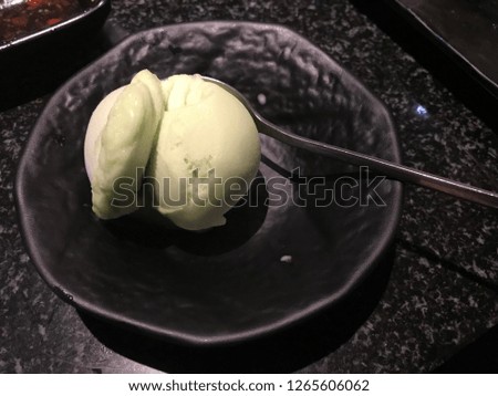 Lime ice cream in cup with stainless steel spoon