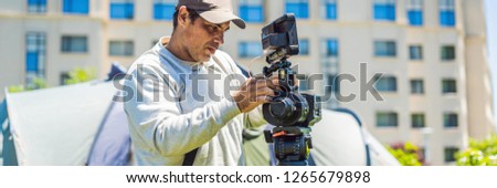 a professional cameraman prepares a camera and a tripod before shooting BANNER, LONG FORMAT
