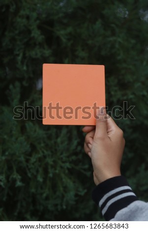 Women hand holding orange empty sign board with abstract background.