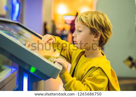 The boy in the yellow jacket uses a touch screen