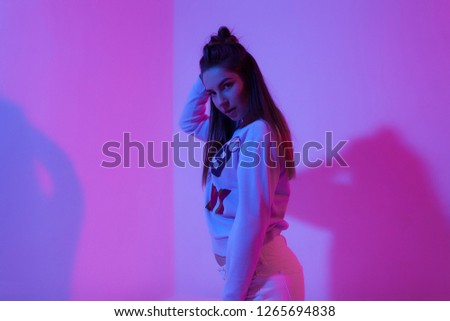 young girl photo shoot in purple light in a light jacket bike and white pants purple rap studio