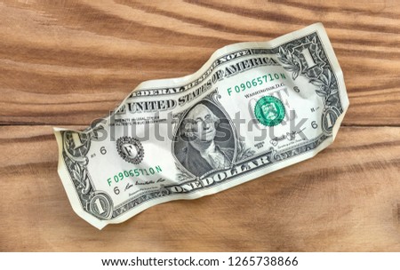 Crumpled one dollar bill on wooden background. Top view.