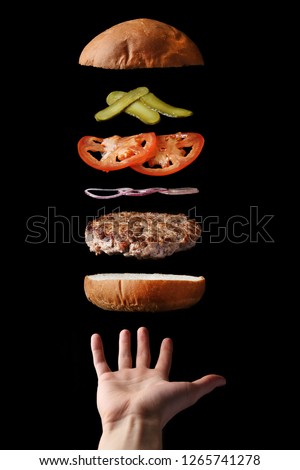 fly burger with beef sliced tomatoes pickles and onion on black. floating food levitating burger Royalty-Free Stock Photo #1265741278