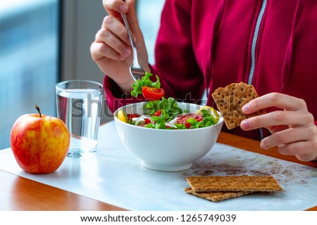 Young woman is eating a healthy, fresh, vegetable salad with crisp rye bread. Diet and healthy lifestyle concept. Diet and fiber food. Proper nutrition and eat right  Royalty-Free Stock Photo #1265749039