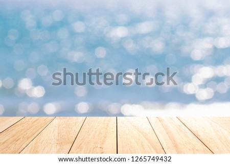 Empty wooden desk table with blue sea bokeh background. Ready for product display montage,copy space.
