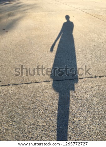 Shadow of a woman while she was walking in the evening during the summer time.