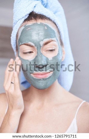 Woman applying mask moisturizing skin cream on face looking in bathroom mirror. Girl taking care of her complexion layering moisturizer. Skincare spa treatment