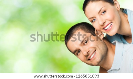 Young happy smiling attractive couple, outdoors. To provide maximum quality, I have made this image, by combination of three photos. You can use left part for slogan, big text or banner.
