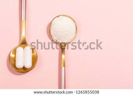 Collagen powder and pills on pink background. Extra protein intake. Natural beauty and health supplement for skin, bones, joints and gut. Plant or fish based. Flatlay, top view. Copy space text. Royalty-Free Stock Photo #1265855038
