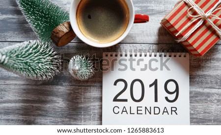 2019 Calendar flat lay with gift box, coffee cup and Christmas trees on rustic grey painted wood planks background. Hello new year, goal setting, start making resolutions theme. (close up, top view)