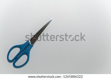 A pair of blue scissors at the lower left corner on white background 
