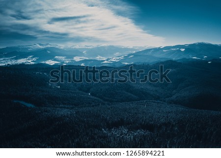 Beautiful aerial drone landscape shot of Carpathian mountains in cold winter day.Forest trees,dramatic sky & snow in Carpahtians.Travel destination for active tourism in Southern Europe