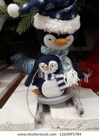 Toy penguin in a scarf sits on a sleigh.