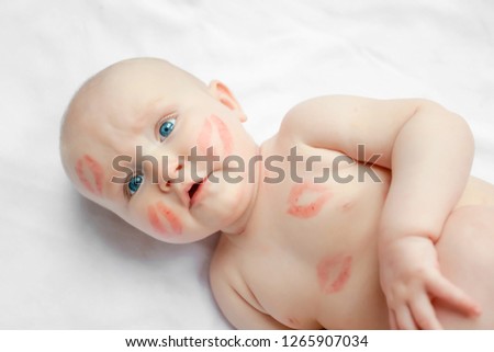 Portrait of a funny newborn baby with red kisses on the skin on white background, Valentines day concept. top view.