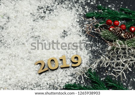 Wooden text numbers on the snow with a Christmas tree and a golden serpentine on the eve of the New Year's holiday in winter