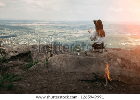 Young girl traveler drinks coffee with a view of the mountain landscape and enjoying the sunrise . Concept adventure active vacations outdoor in the mountains. Summer camping 