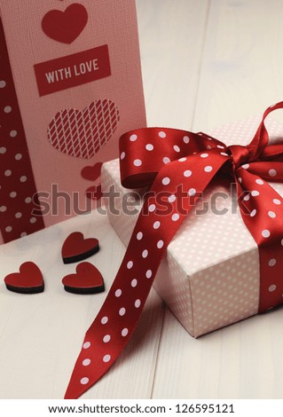 Special occasion handmade gift card, "With Love" message, with pink gift and red polka dot ribbon and hearts on white natural wood table, for Valentine, Christmas, Easter, birthday, or Mothers Day.