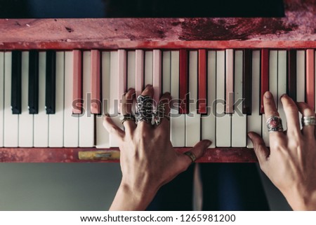 Female hands wearing jewellery rings playing on Pink piano keyboard