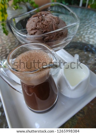 Beaker mug fill with hot coffee and a cup of chocolate icecream on a table