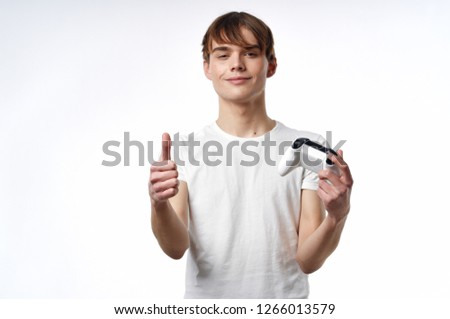 Cheerful guy Gamer in a white T-shirt holding a joystick from the console                      