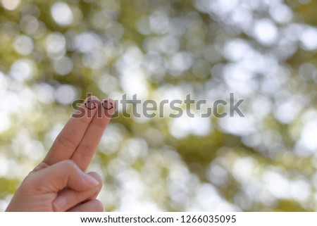 Happy face on fingers with bokeh nature background.