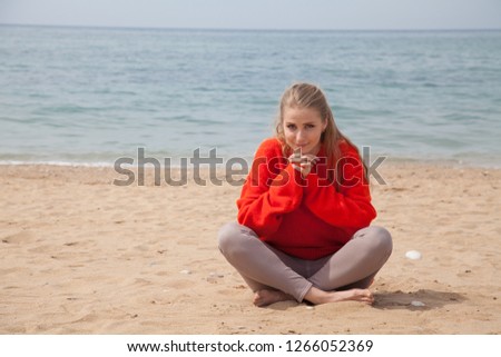 beautiful blonde woman in red walks on sandy sea Beach