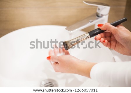 Makr up brush. Woman washing dirty makeup brush with soap and foam in the sink. Royalty-Free Stock Photo #1266059011