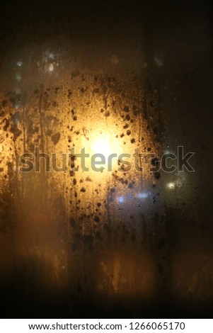 Golden lights on a black background night.  A look through the window. Droplets on the window in the dark - golden glow. 
