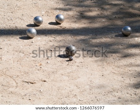  
Petanque balls on the ground. Pétanque is a form of boules where the goal is to toss or roll hollow steel balls as close as possible to a small wooden ball called a cochonnet.