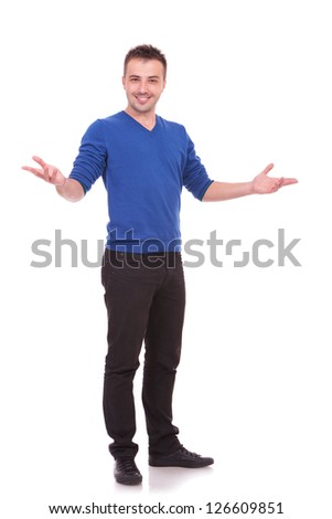 Full length picture of a young casual man welcoming you on white background