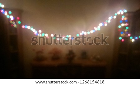Blurred and defocused image. Texture and background, wallpaper of bright, multi-colored Christmas garland in a residential or public room, resembling night stars in the sky. NewYear's holidays, party.