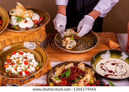 Assembly of salad from dried tomatoes with cheese and olives with salad arugula