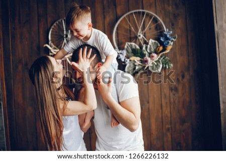 Cute family standing near brown wall. Mother and father have fun with they little son.